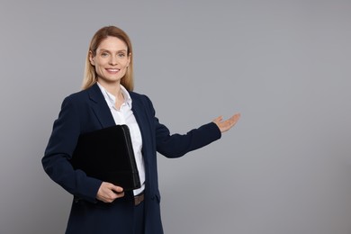 Photo of Happy real estate agent with leather portfolio on grey background. Space for text