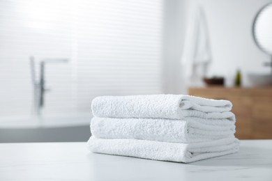 Photo of Stacked bath towels on white table indoors. Space for text