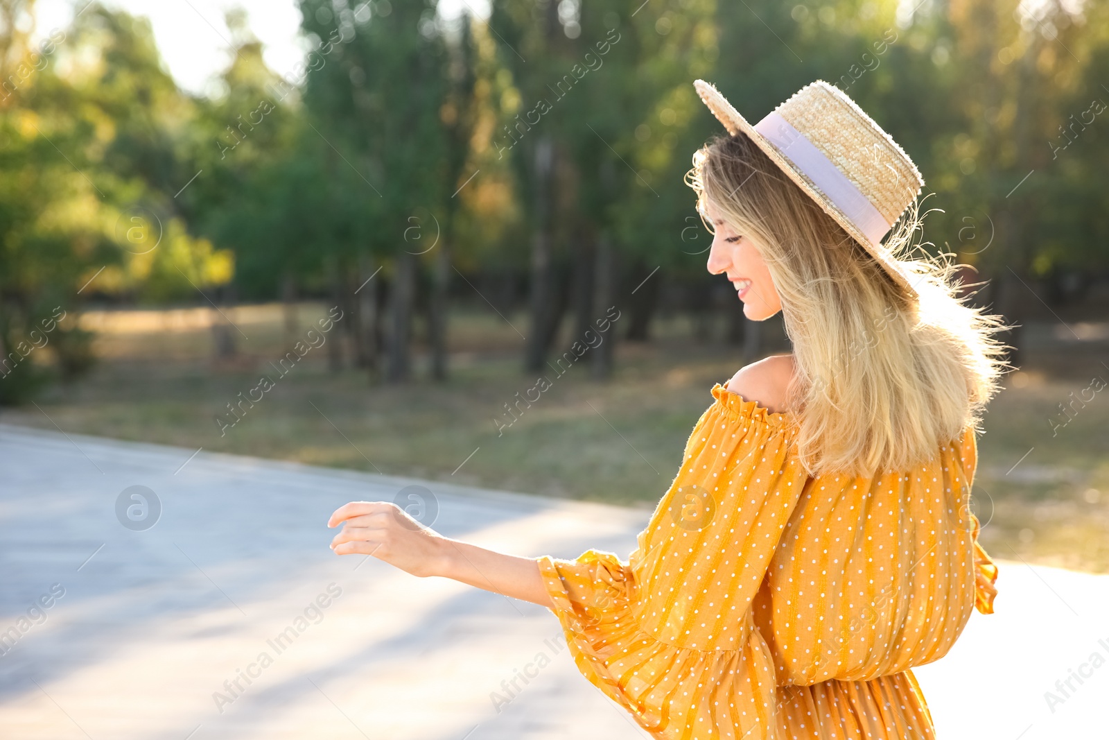 Photo of Beautiful young woman in stylish yellow dress and straw hat outdoors