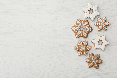 Photo of Christmas snowflake shaped gingerbread cookies on white wooden table, flat lay. Space for text