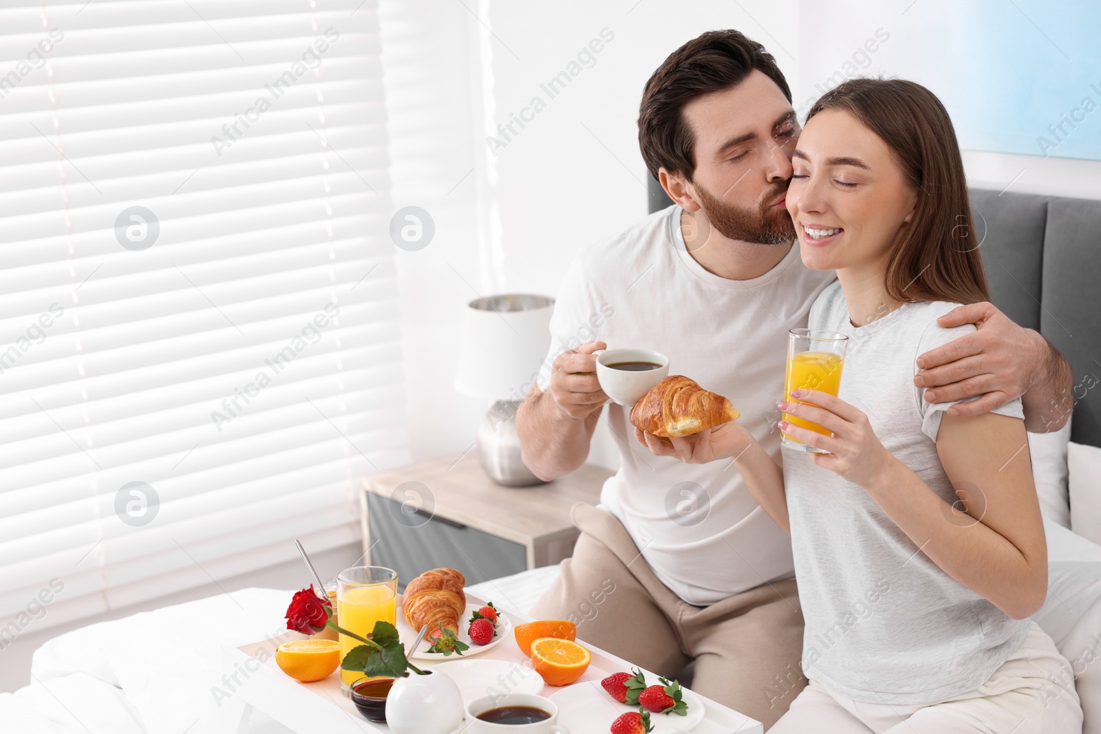 Photo of Lovely couple having breakfast in bedroom. Space for text