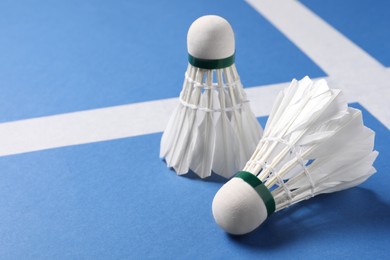 Feather badminton shuttlecocks on blue background, closeup. Space for text