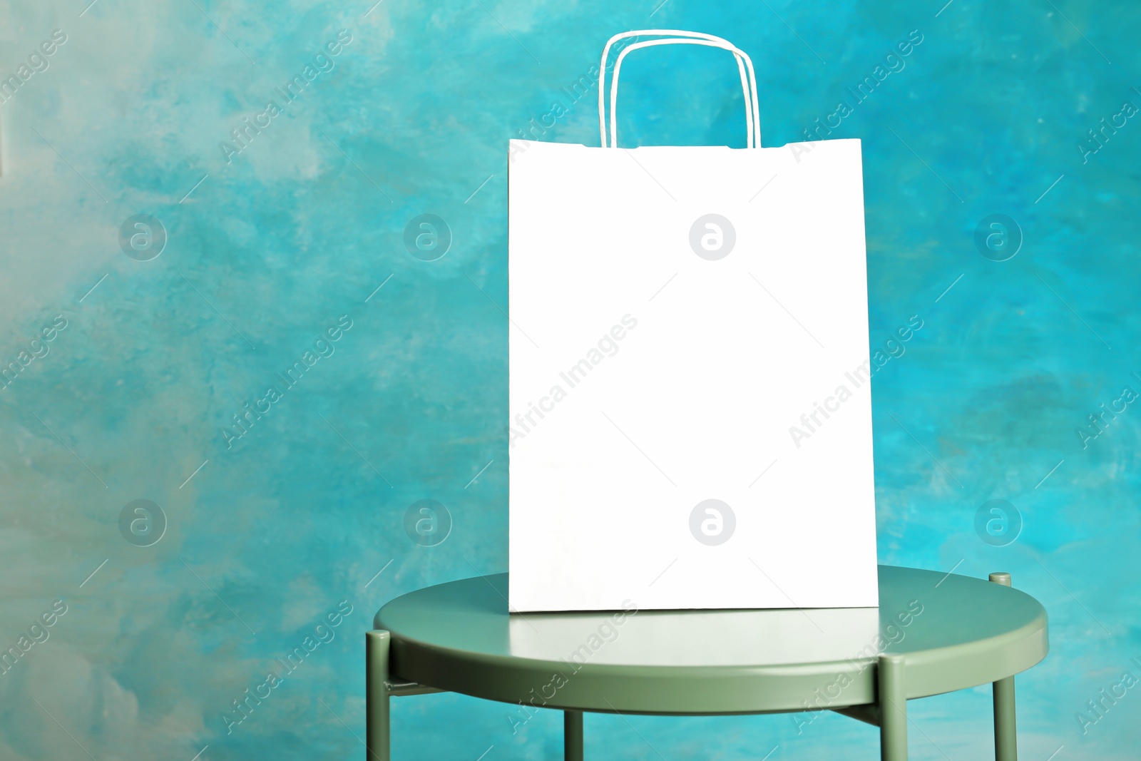 Photo of Mockup of paper shopping bag on table against color background