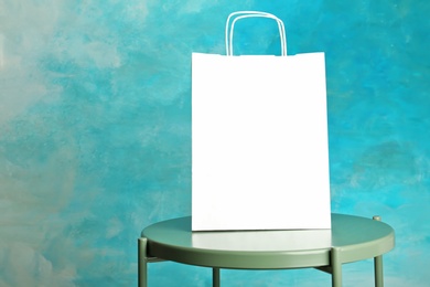 Photo of Mockup of paper shopping bag on table against color background