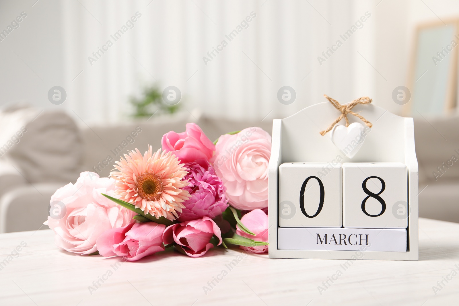 Photo of International Women's day - 8th of March. Block calendar and bouquet of beautiful flowers on white wooden table