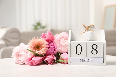 Photo of International Women's day - 8th of March. Block calendar and bouquet of beautiful flowers on white wooden table