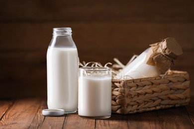 Photo of Tasty fresh milk in bottles and glass on wooden table