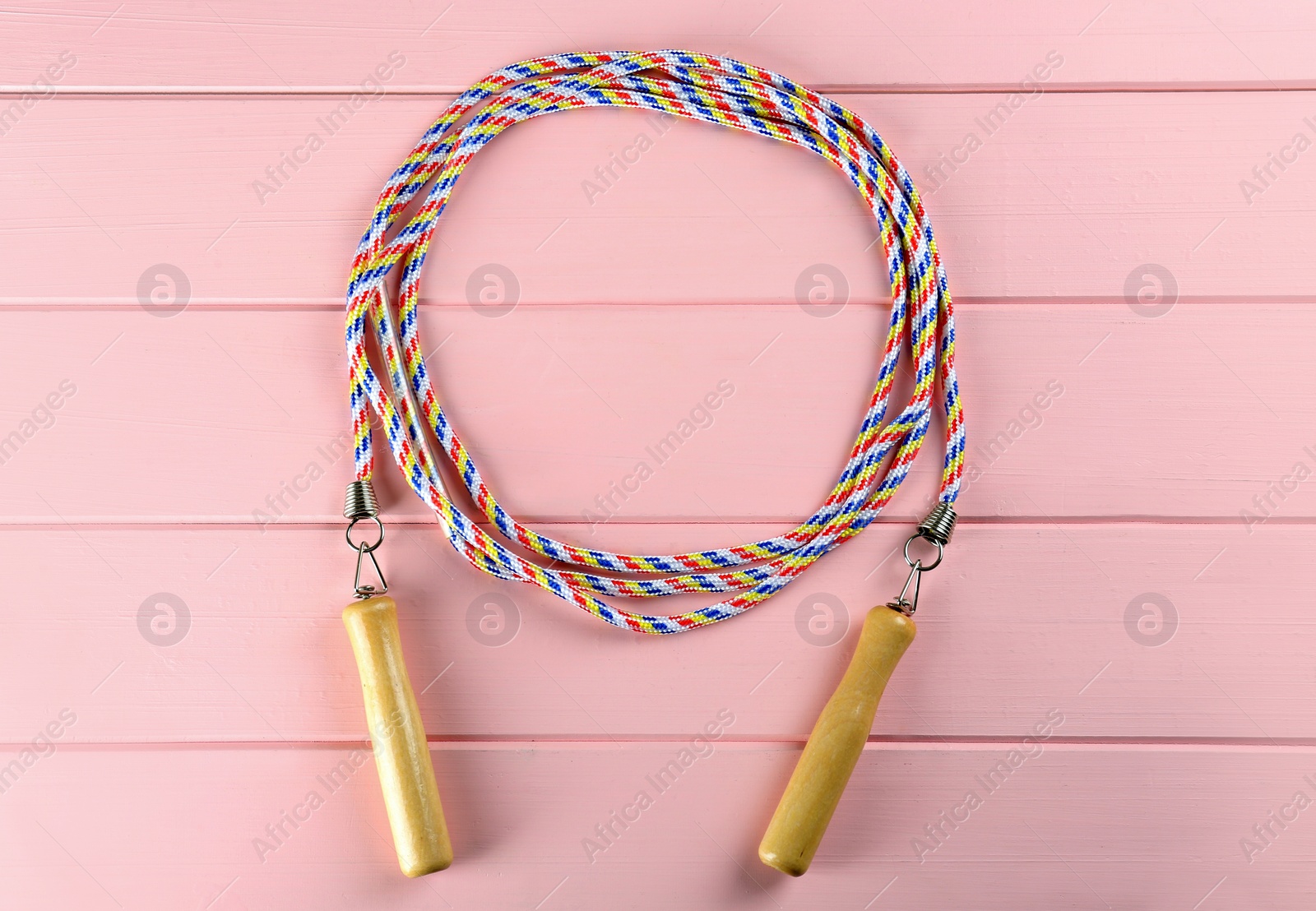 Photo of Skipping rope on pink wooden table, top view. Sports equipment