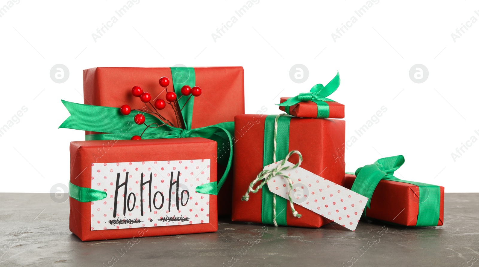 Photo of Many Christmas gifts with red berries on grey table against white background