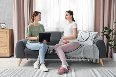 Doula working with pregnant woman on sofa at home. Preparation for child birth