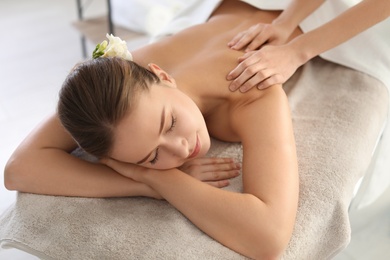 Photo of Young woman enjoying massage in spa salon