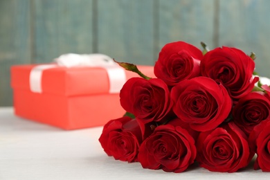 Beautiful red roses and gift box on white table, space for text. St. Valentine's day celebration