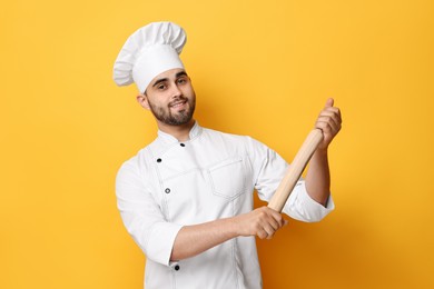 Professional chef with rolling pin on yellow background
