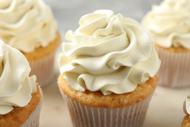 Tasty cupcakes with vanilla cream on table, closeup