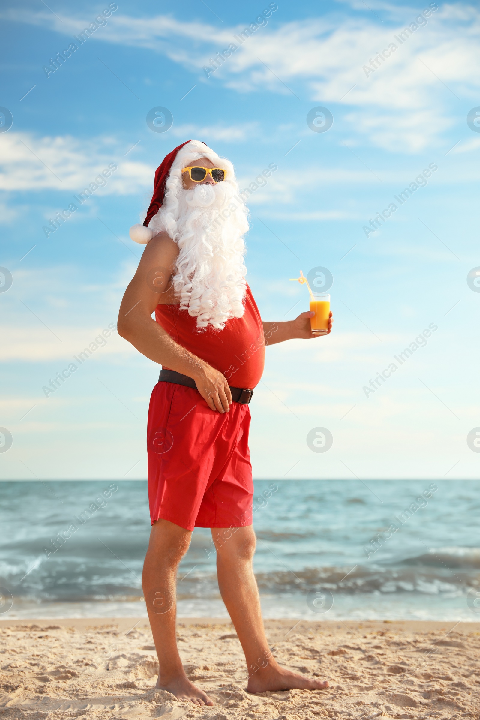 Photo of Santa Claus with cocktail on beach. Christmas vacation