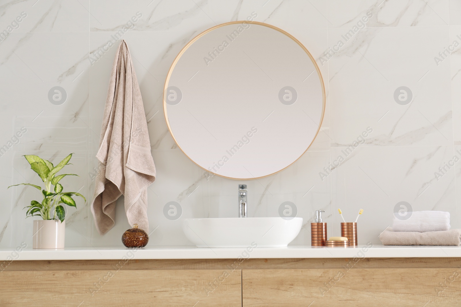 Photo of Round mirror over vessel sink in stylish bathroom interior