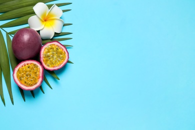 Passion fruits (maracuyas), flower and palm leaf on light blue background, flat lay. Space for text