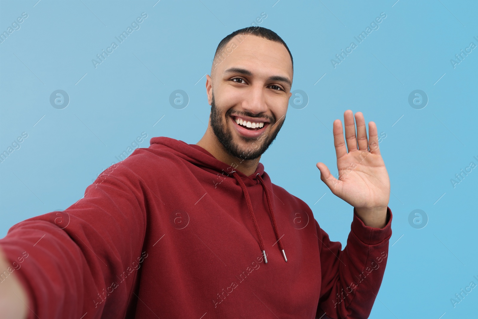 Photo of Smiling young man taking selfie on light blue background