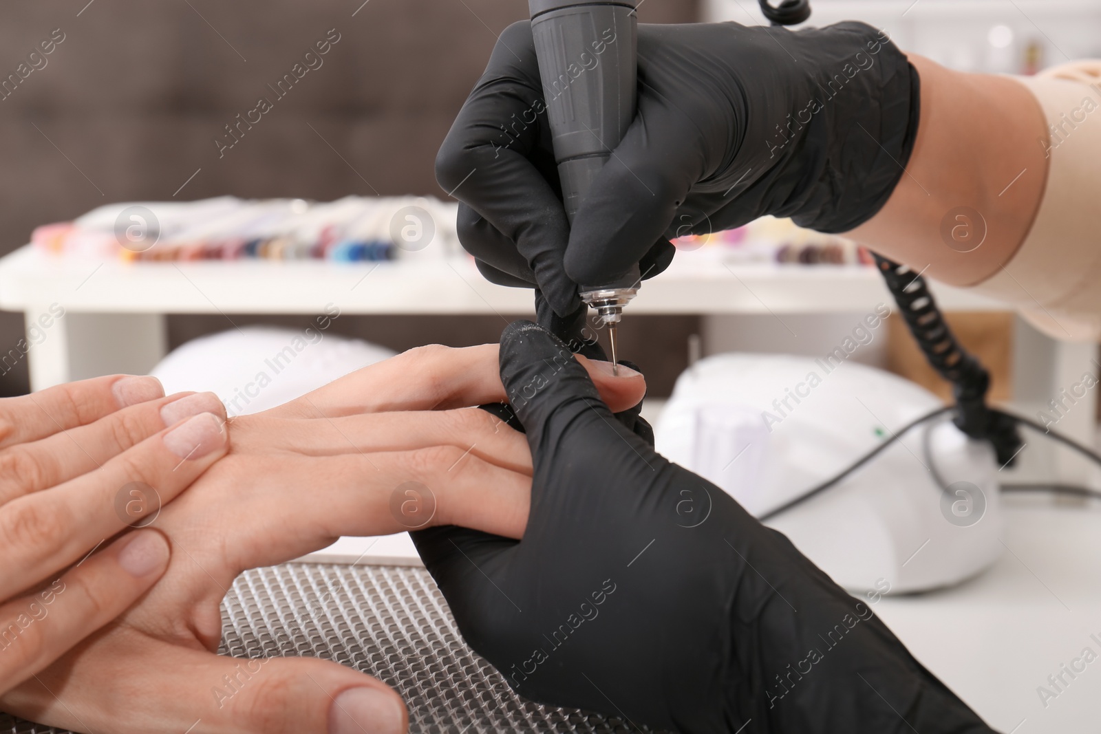 Photo of Professional manicurist working with client in salon, closeup