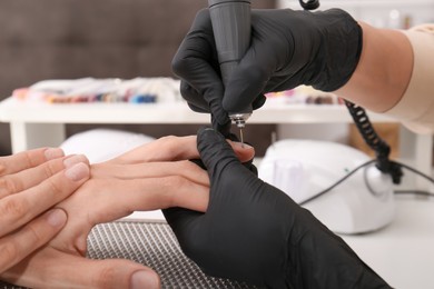 Photo of Professional manicurist working with client in salon, closeup