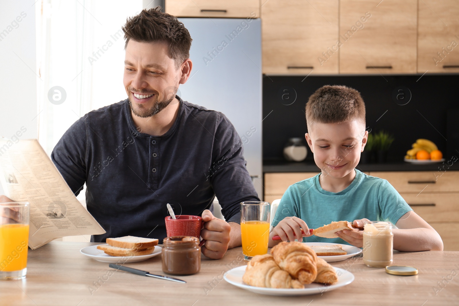 Photo of Dad and son having breakfast together in kitchen