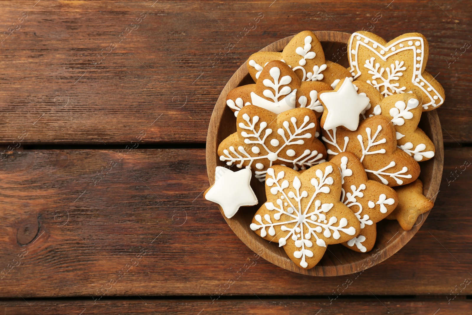 Photo of Tasty Christmas cookies with icing in bowl on wooden table, top view. Space for text