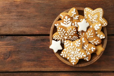 Photo of Tasty Christmas cookies with icing in bowl on wooden table, top view. Space for text