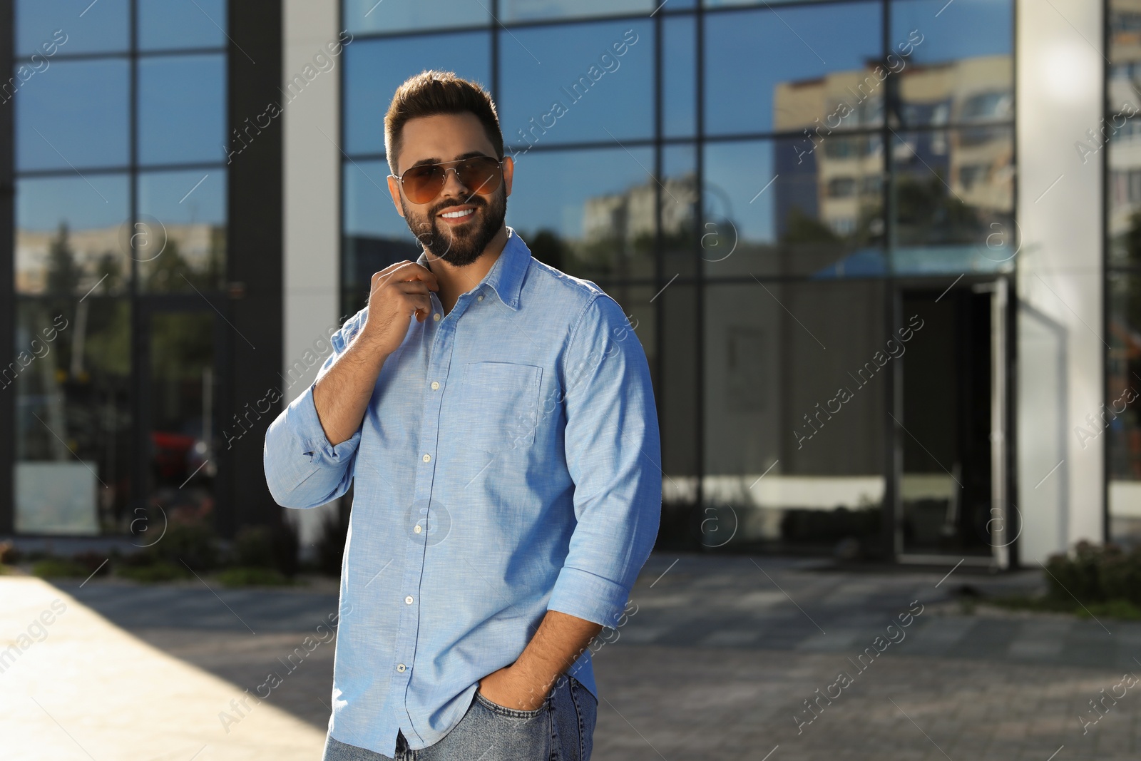 Photo of Handsome smiling man in sunglasses on city street, space for text
