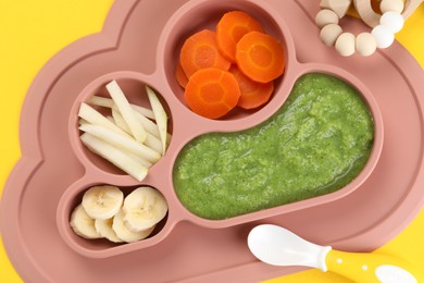 Healthy baby food. Section plate with delicious broccoli puree, vegetables and fruit on yellow background, top view