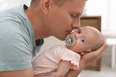 Photo of Happy father holding his cute little baby at home, closeup