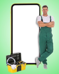 Image of Repair service - just call. Happy professional repairman, toolbox and smartphone with blank screen on light green background, space for design