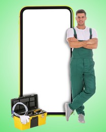 Repair service - just call. Happy professional repairman, toolbox and smartphone with blank screen on light green background, space for design