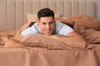 Photo of Man lying in bed with brown linens at home