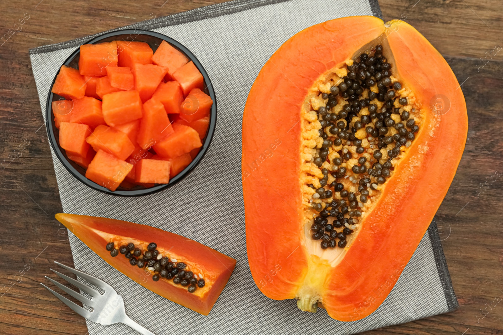 Photo of Tasty cut papaya fruits on wooden table, flat lay