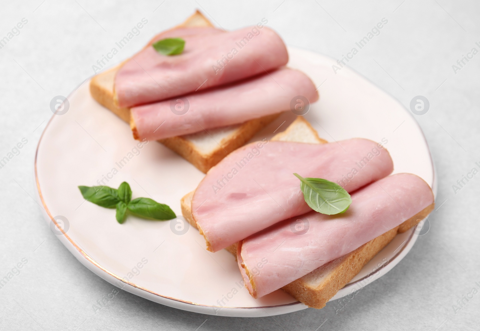 Photo of Delicious sandwiches with ham on light gray table, closeup