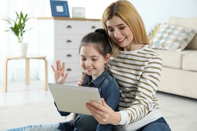 Photo of Mother and her daughter using video chat on tablet at home