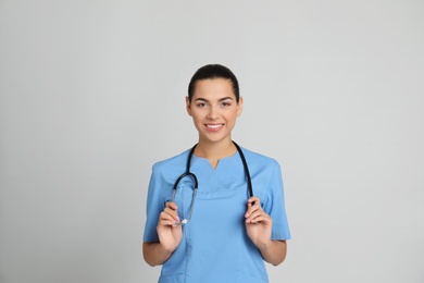 Portrait of young medical assistant with stethoscope on color background