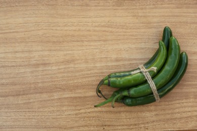 Photo of Green ripe chili peppers on wooden table, top view. Space for text