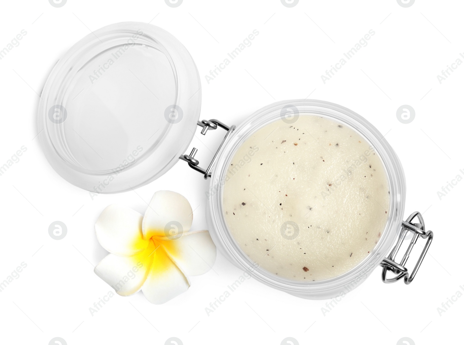 Photo of Jar of exfoliating salt scrub and plumeria flower on white background, top view