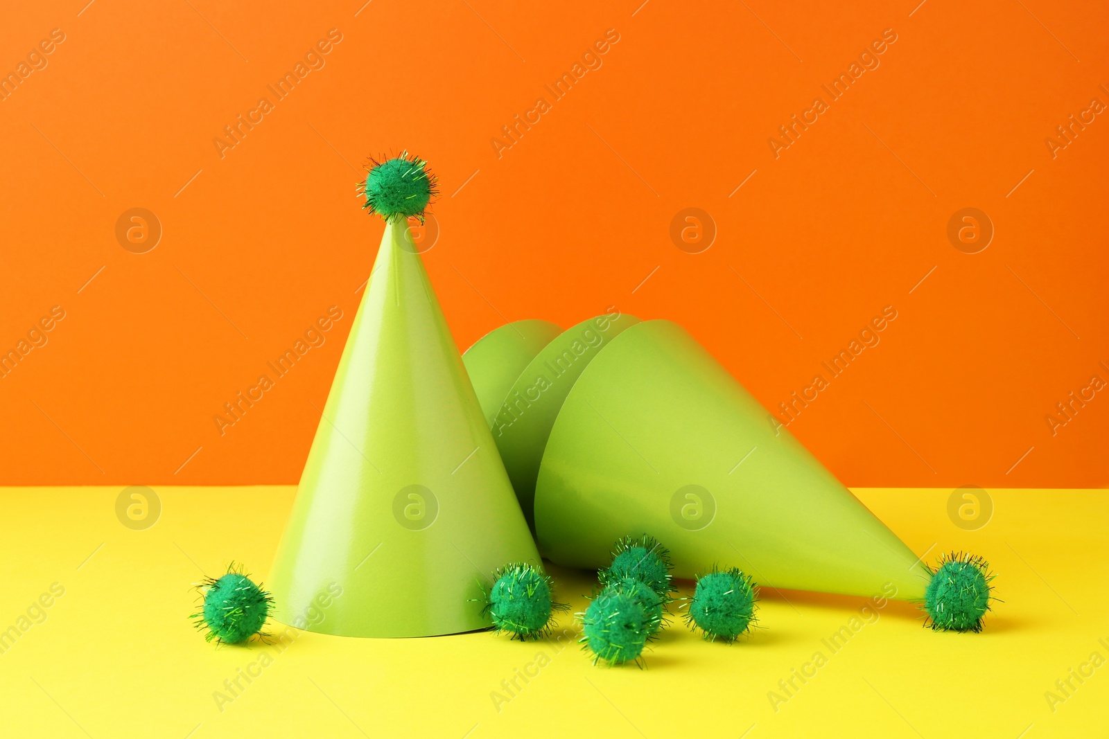 Photo of Party hats on yellow table against orange background