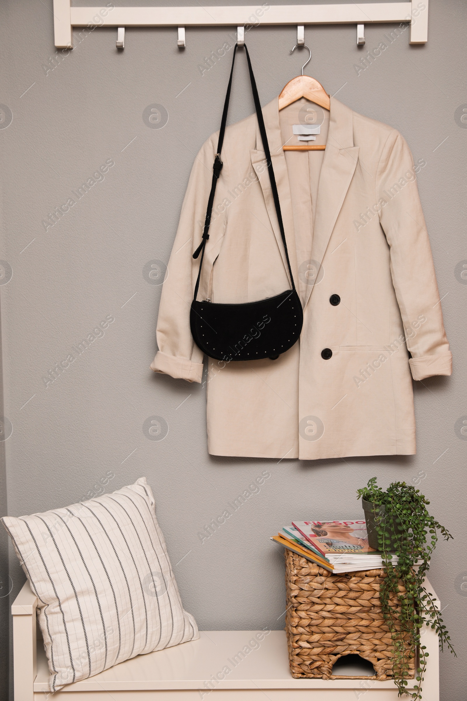 Photo of Bench and coat rack on grey wall in hallway. Interior element