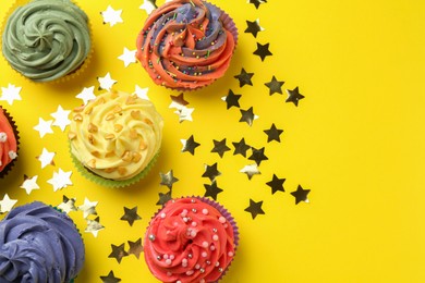 Delicious cupcake with bright cream and shiny confetti on yellow background, flat lay. Space for text