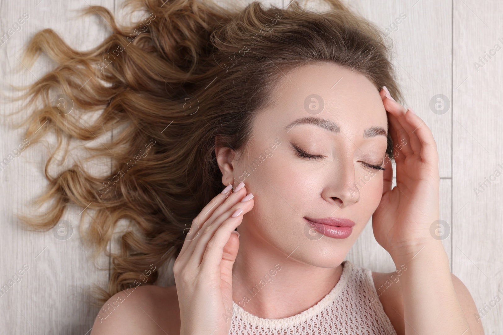 Photo of Portrait of beautiful woman with closed eyes on wooden floor, top view