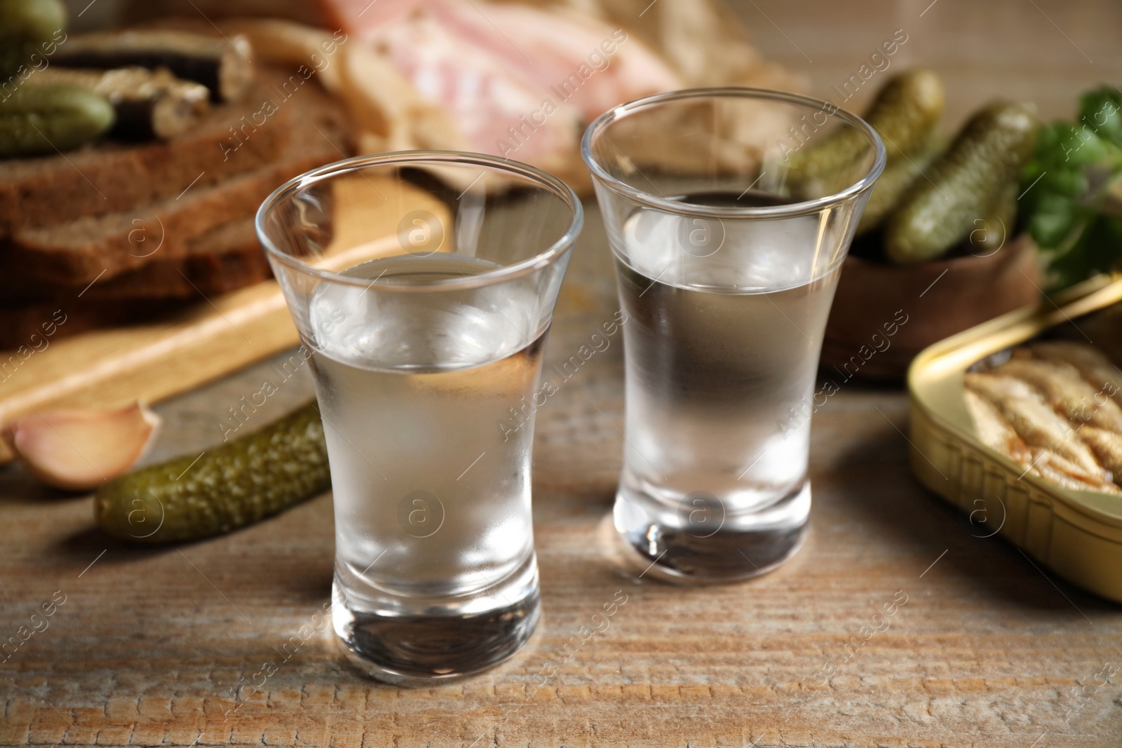 Photo of Cold Russian vodka with snacks on wooden table, closeup