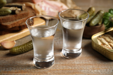 Photo of Cold Russian vodka with snacks on wooden table, closeup