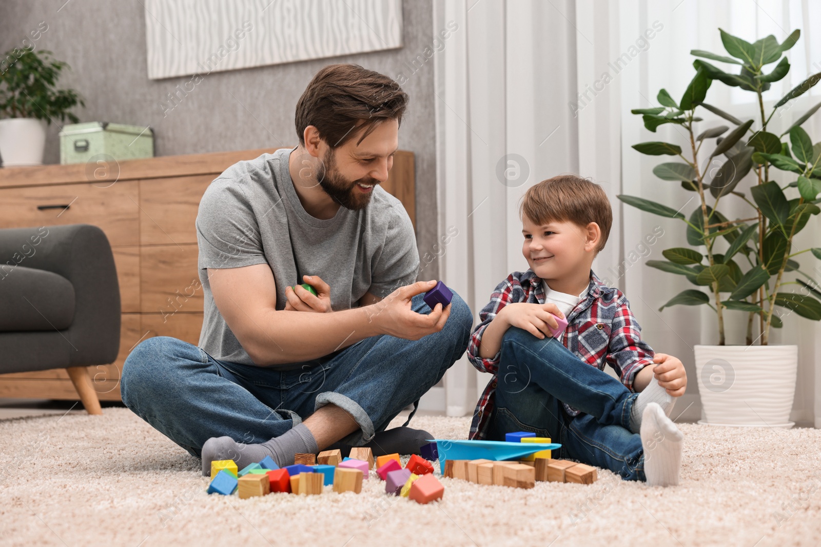 Photo of Happy dad and son playing with cubes at home