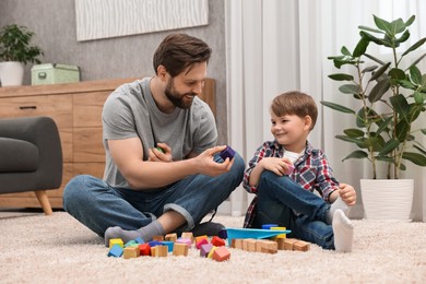 Happy dad and son playing with cubes at home