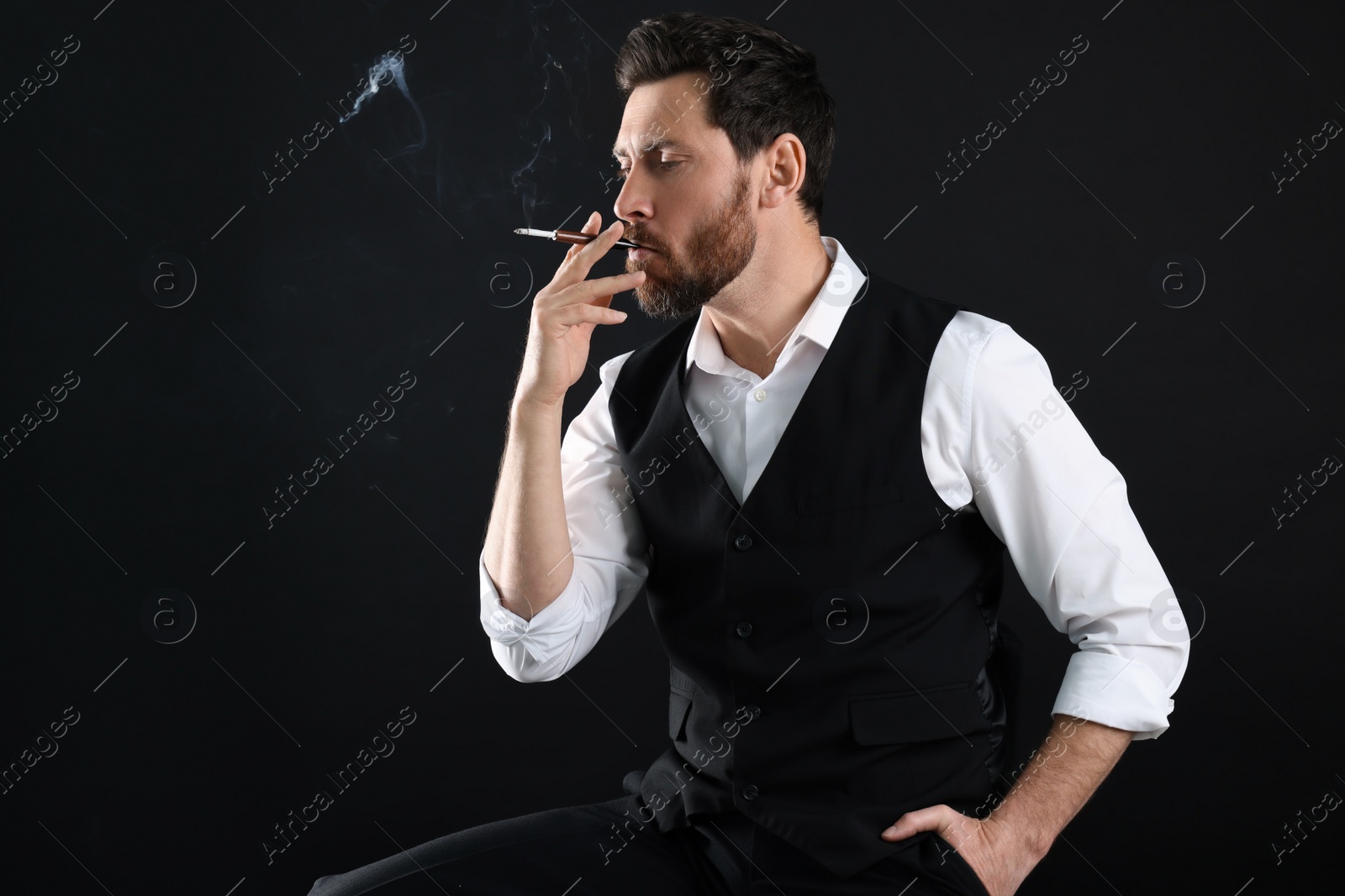 Photo of Man using cigarette holder for smoking on black background, space for text