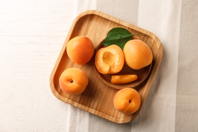 Photo of Plates with delicious apricots on white wooden background, top view