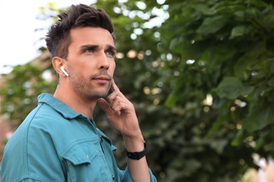 Young man with wireless earphones in park